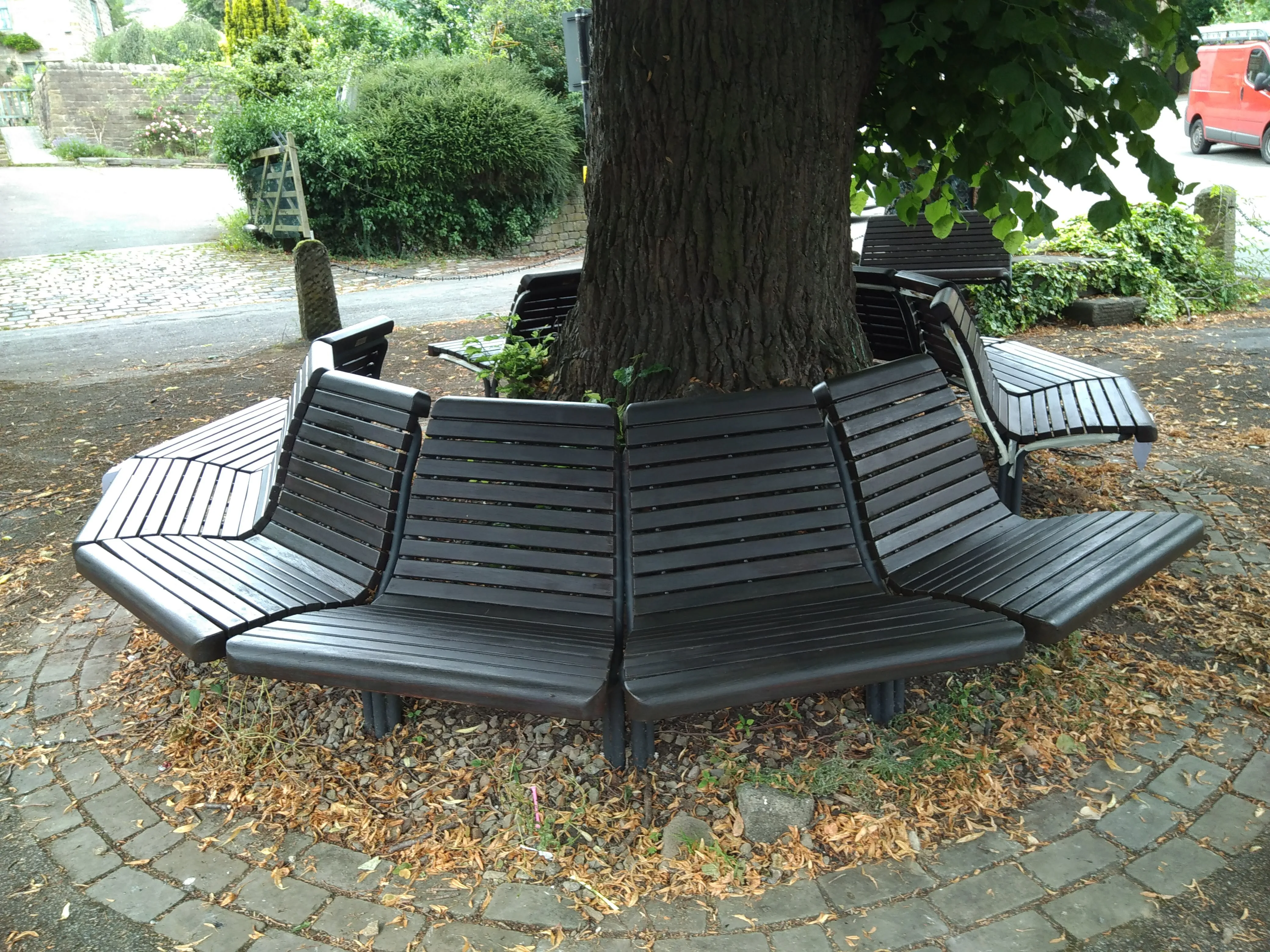 A couple of park benches sitting under a tree.